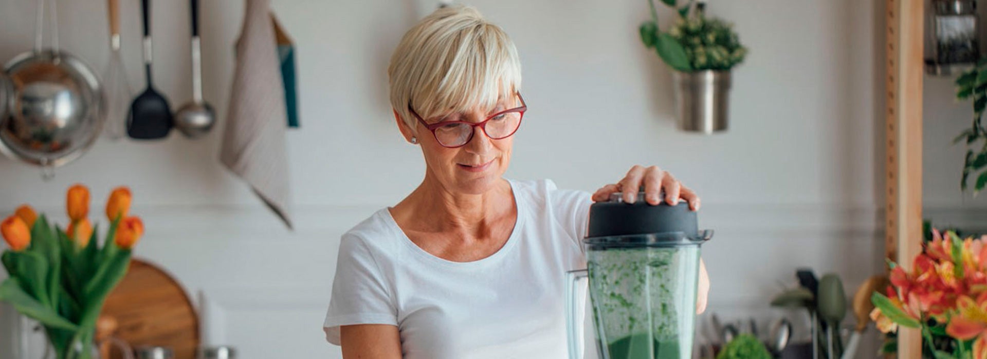 Mulher preparando um suco verde fresco na cozinha, representando hábitos saudáveis